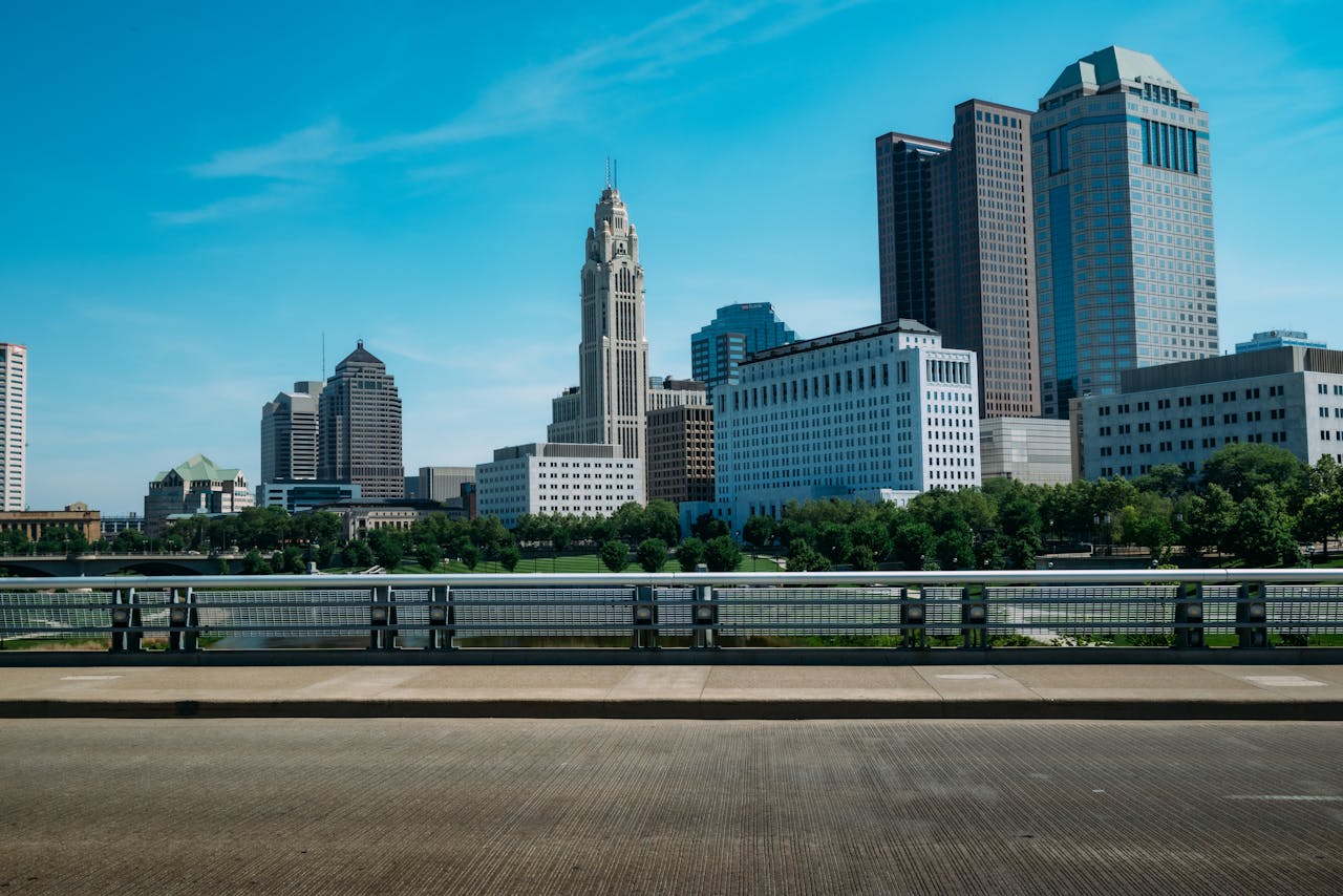 View of Columbus skyline featuring high-rise buildings against a blue sky, with urban trees.